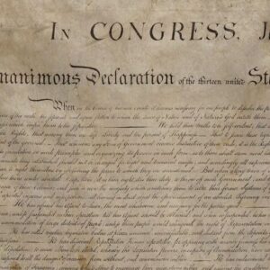 A close-up of the Declaration of Independence showing handwritten, cursive text on aged, yellowed paper with the words In CONGRESS clearly visible at the top.