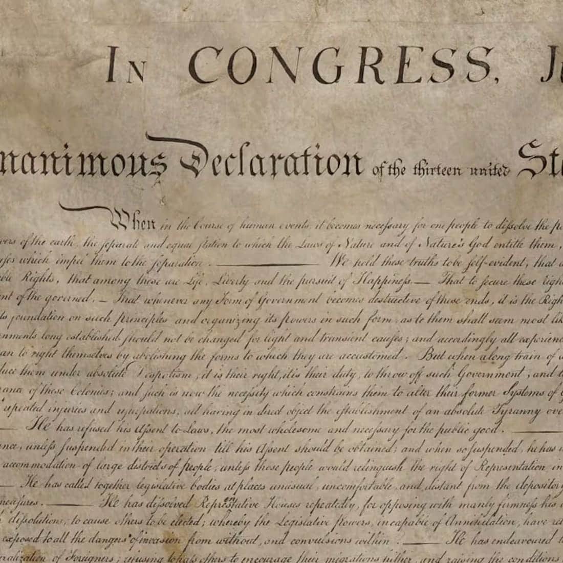 A close-up of the Declaration of Independence showing handwritten, cursive text on aged, yellowed paper with the words In CONGRESS clearly visible at the top.